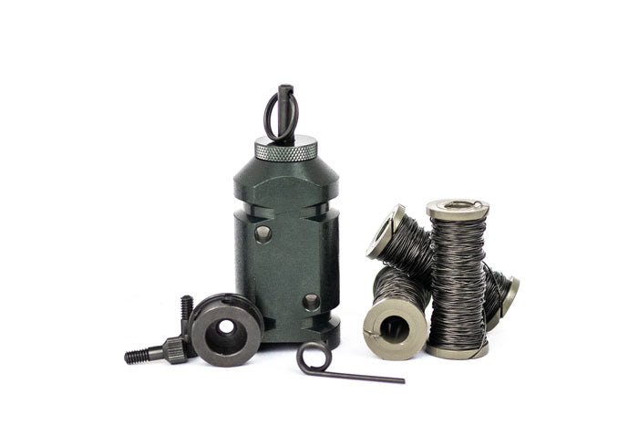 The 12g perimeter trip alarm sitting on its flat bottom, next to the 308 adapter on its side, with 3 spools of military trip wire. Complete kit for camping, hiking, backpacking